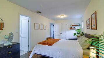 A bedroom with a bed, bedside tables, a dresser, a mirror, and a ceiling fan.