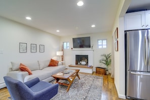 Una sala moderna con sofá, sillón, mesa de centro, chimenea y un refrigerador grande.