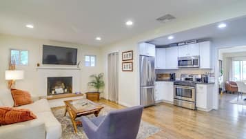 A spacious living area with a fireplace, a television, and a kitchen with modern appliances.