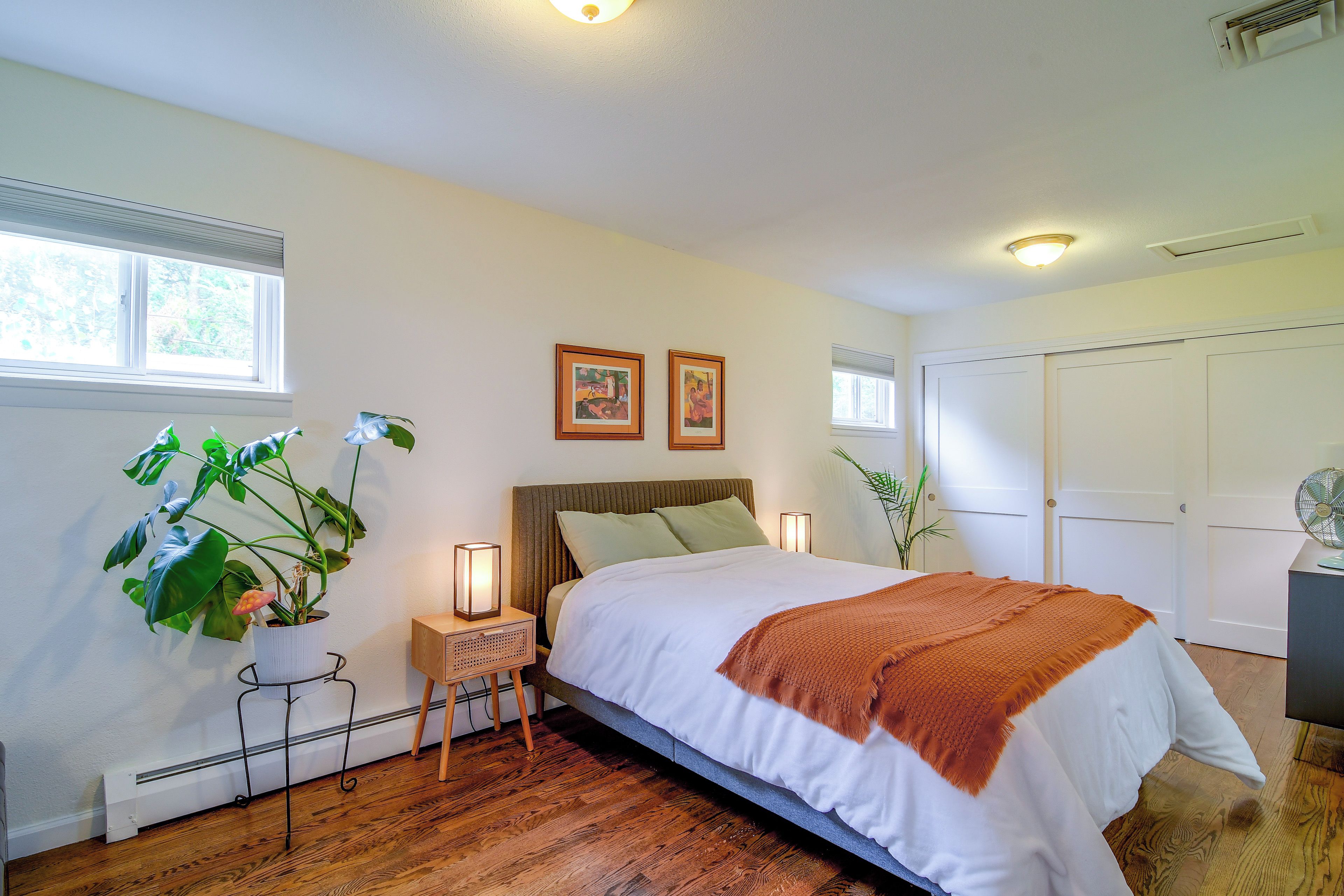 Une chambre à coucher avec un lit, des lampes de chevet, un radiateur et deux tableaux encadrés accrochés au mur.