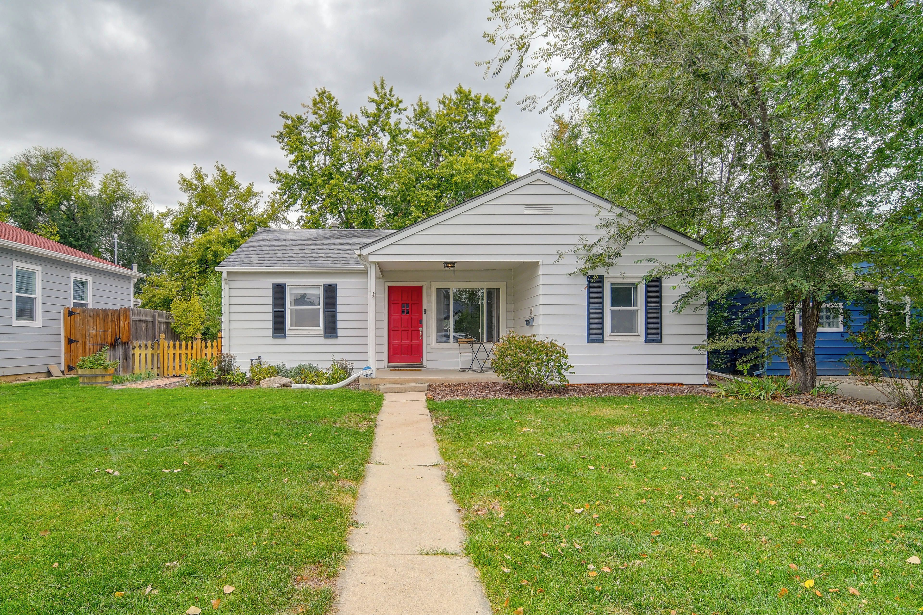 A single-story house with a red door and a small front yard.