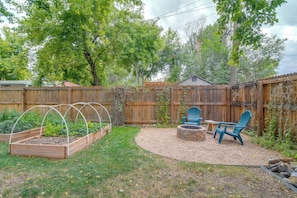 A backyard with raised garden beds, a fire pit, and outdoor seating.