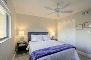 A bedroom with a bed, two bedside tables with lamps, a ceiling fan, and a door. - Pool Access & Lanai! Updated Fort Myers Condo (Fort Myers)