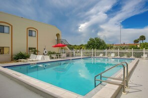 A clear blue pool with a white fence, lounge chairs, and a red umbrella. - Pool Access & Lanai! Updated Fort Myers Condo (Fort Myers)