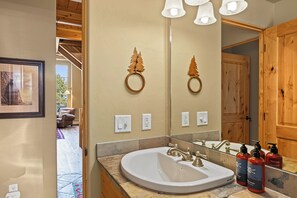 A bathroom with a large mirror, wooden decor, a sink with a single faucet, and a window with a view of the outdoors. - Moonlit Hearth & Hickory | Ski-In/Out + Hot Tub (Big Sky)