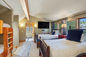 A bedroom with two beds, a TV, and a window with curtains. - Moonlit Hearth & Hickory | Ski-In/Out + Hot Tub (Big Sky)