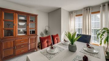A dining area with a wooden cabinet, a table set with plates, and a window with curtains.