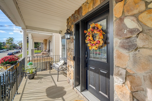 A stone exterior with a black door, a porch with a bench, and a railing.