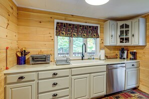 A kitchen with wooden walls, a window with a patterned valance, a built-in dishwasher, and a coffee maker. - 1/2 Mi to Marina! Lake George Group Getaway (Diamond Point)