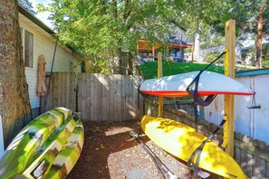 A backyard with a wooden fence, a covered area with a white and red canopy, and two kayaks. - Dock + Year-round Fishing! Lakefront Michigan Home (Newaygo)