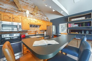 Una cocina con armarios de madera, electrodomésticos de acero inoxidable y una isla central con un libro encima.