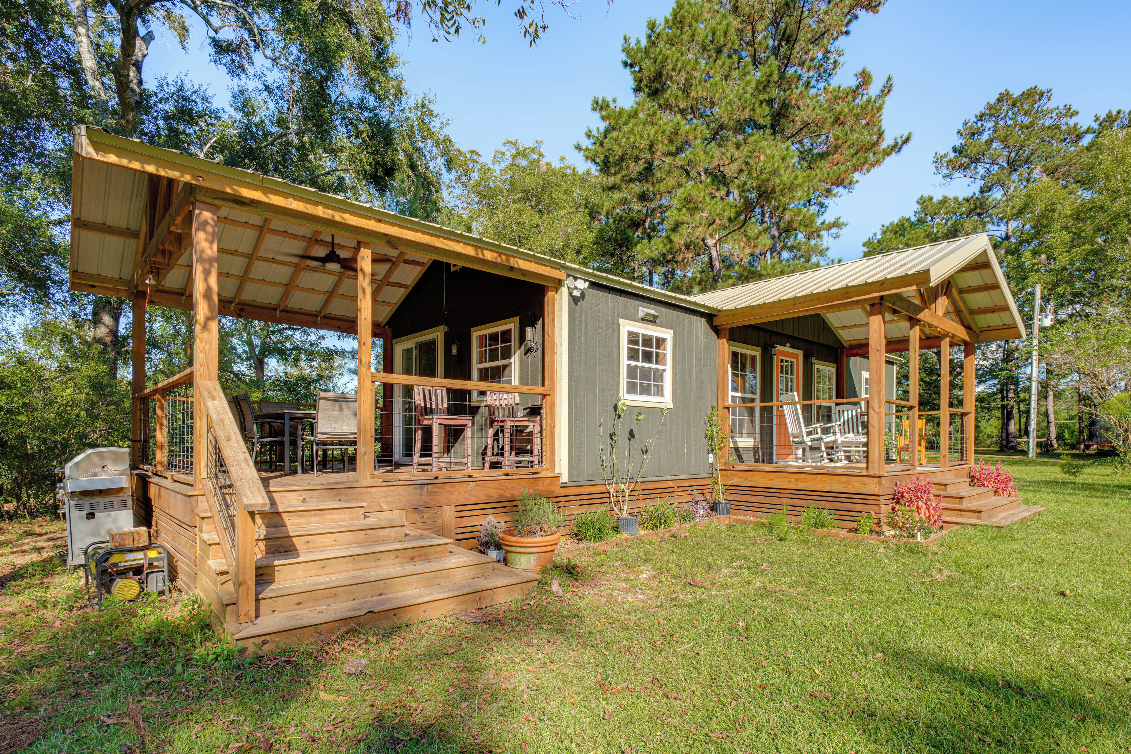 A wooden cabin with a porch, outdoor seating, and a grill area.