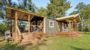 A wooden cabin with a porch, outdoor seating, and a grill area.