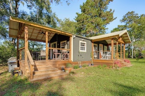A wooden cabin with a porch, outdoor seating, and a grill area.