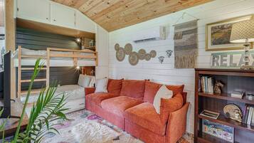 A cozy room with a bunk bed, a red sofa, a bookshelf, and a decorative wall.