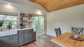 A modern kitchen with a wooden ceiling, a large window, and a dining area with a table and chairs.
