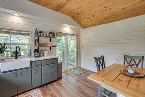 A modern kitchen with a wooden ceiling, a large window, and a dining area with a table and chairs.
