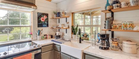 A kitchen with a large window, wooden cabinets, and various kitchen appliances.