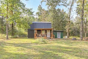 A small cabin with a porch, surrounded by trees.