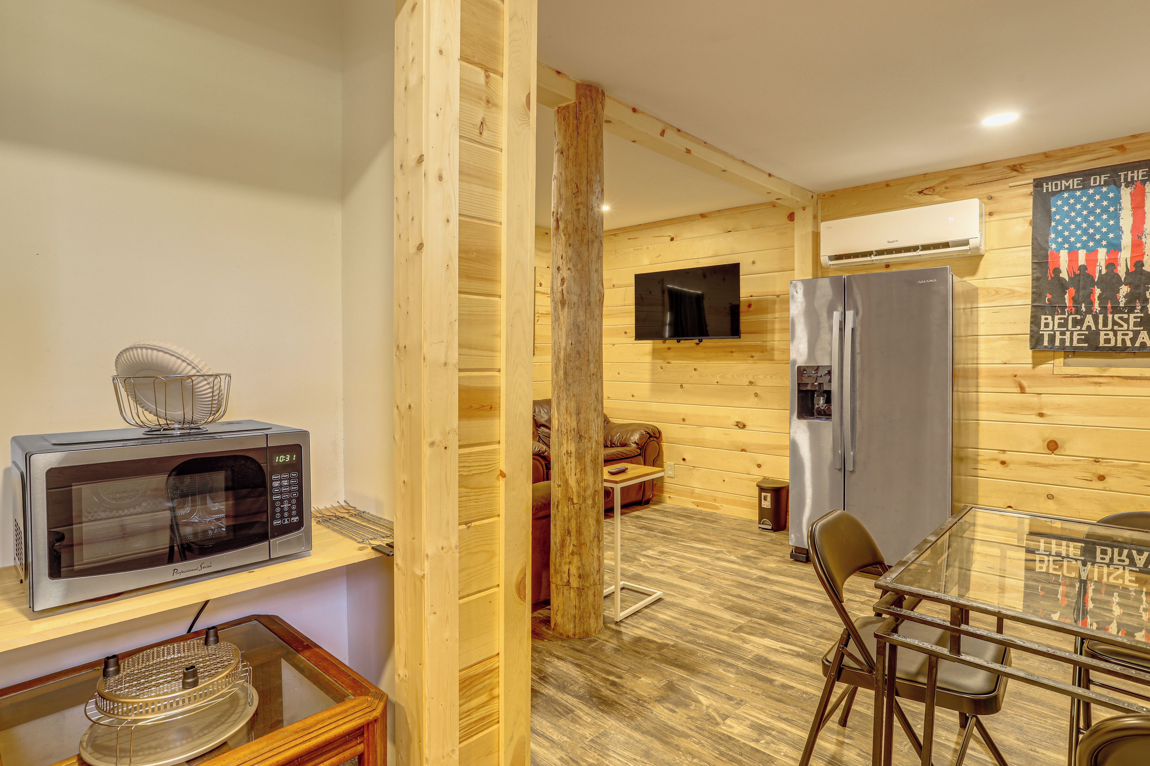 A compact kitchen with a microwave, a refrigerator, and a dining area with a table and chairs.