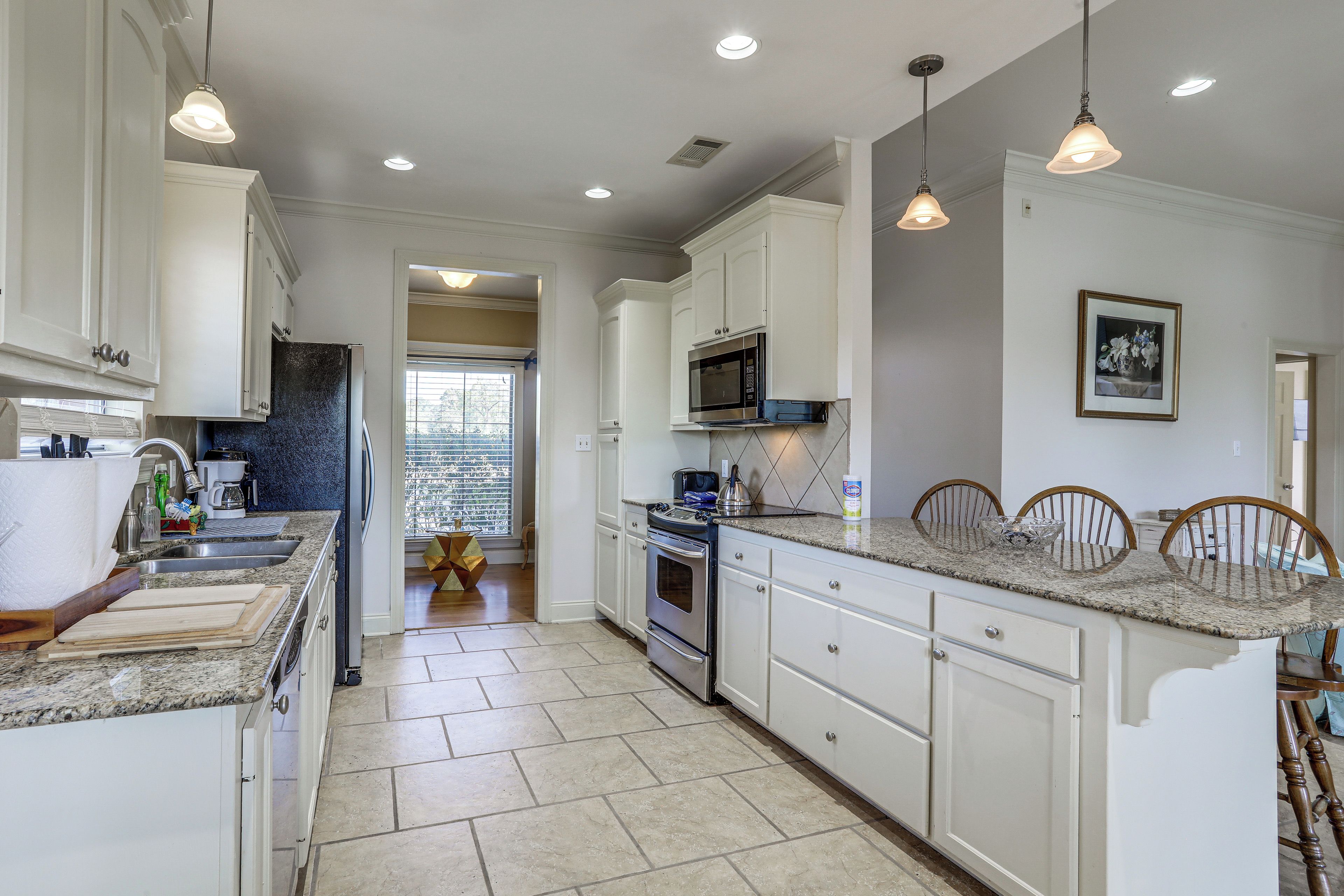 A kitchen with white cabinets, granite countertops, a built-in oven, and pendant lighting.