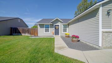 A residential house with a front yard, a wooden fence, and two flower planters.