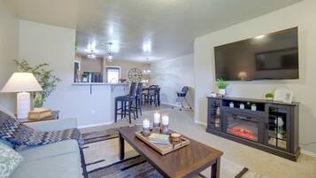 A living room with a fireplace, a television mounted on the wall, and a dining area in the background.