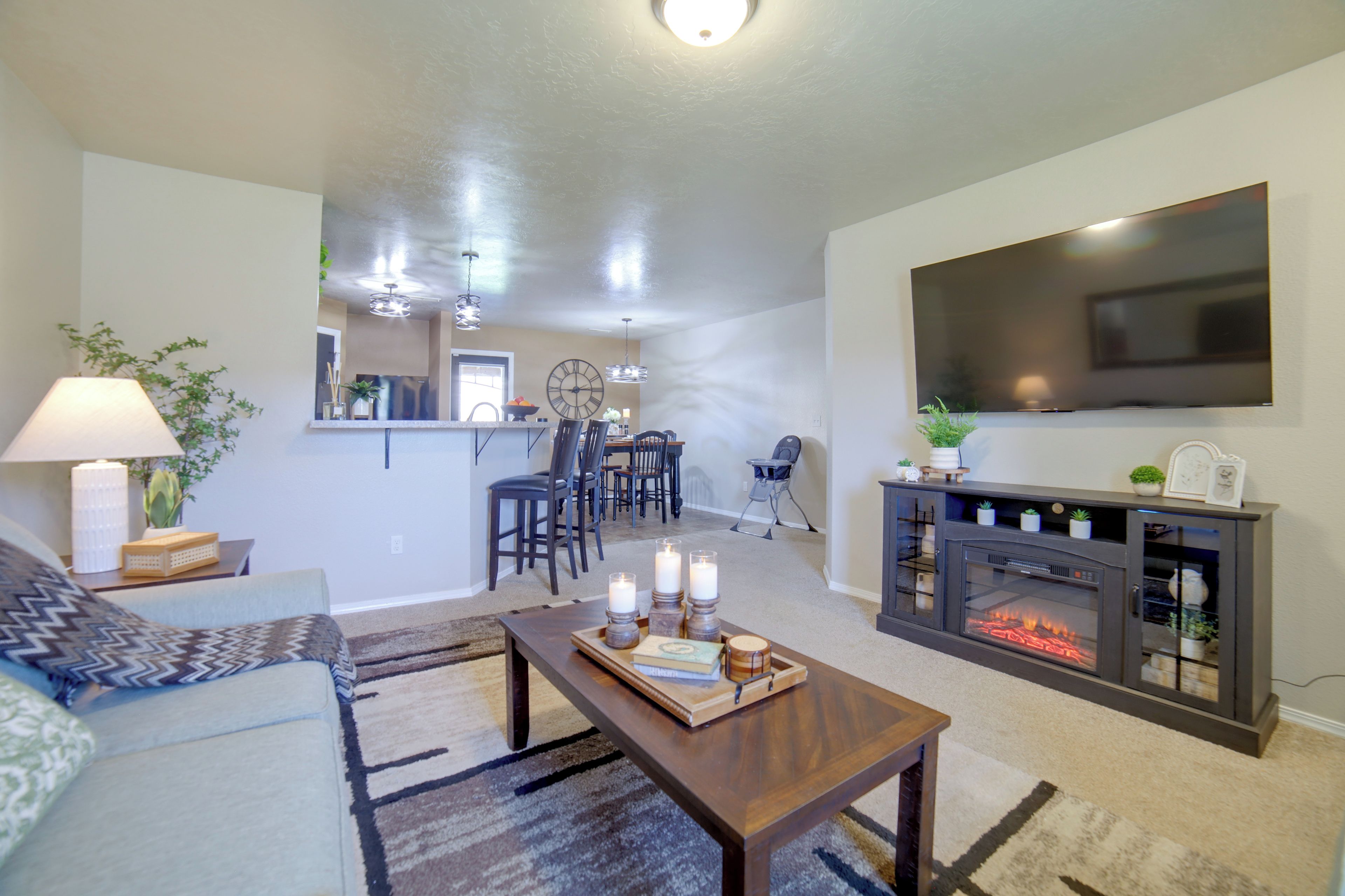 A living room with a fireplace, a television mounted on the wall, and a dining area in the background.