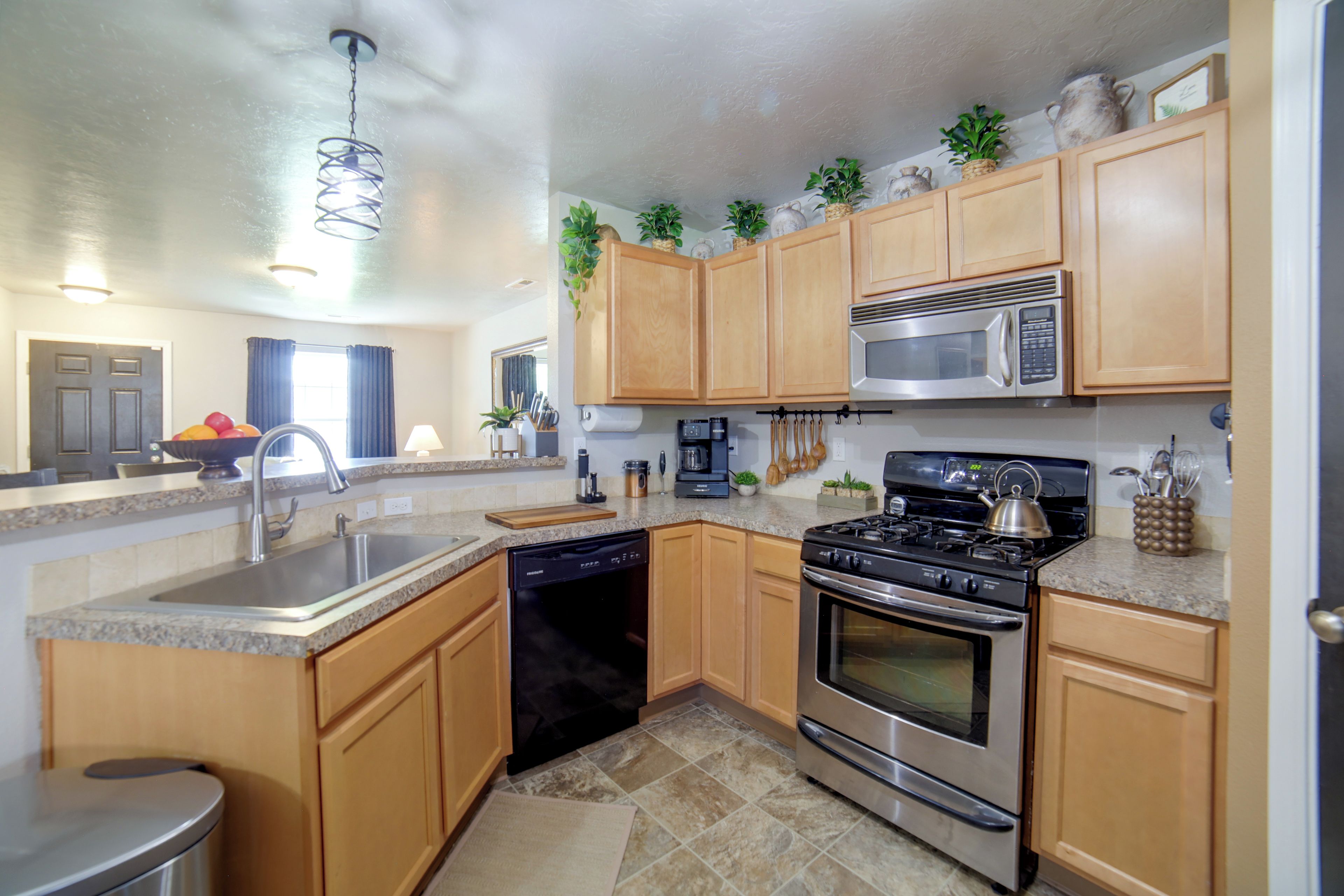 A modern kitchen with wooden cabinets, stainless steel appliances, and a granite countertop.