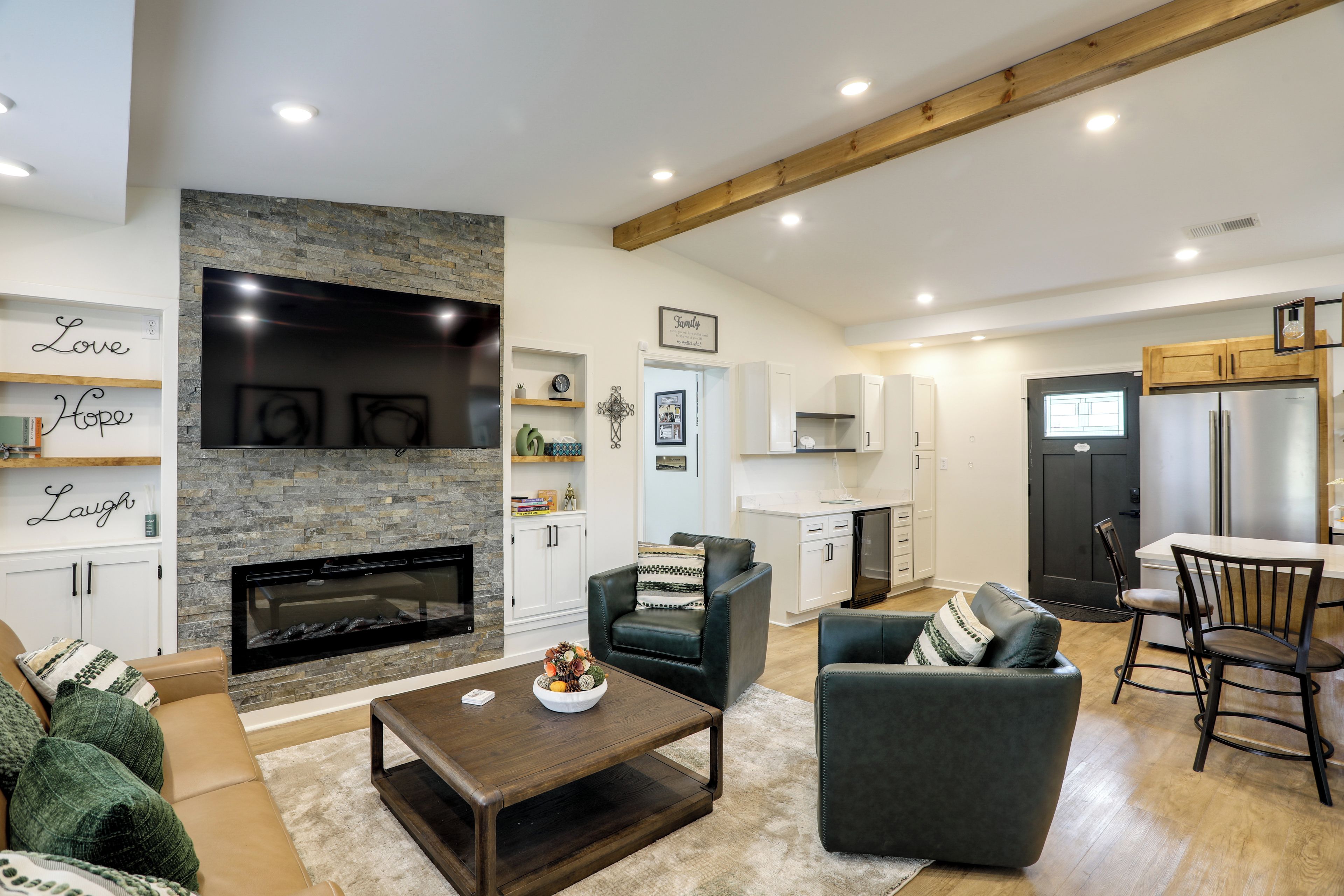 A modern living room with a fireplace, a dining area with a kitchen in the background, and a cozy seating arrangement.