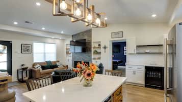 A modern kitchen with a marble island, stainless steel appliances, and a dining area with a vase of flowers.