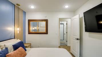 Une chambre à coucher comprenant un lit, un téléviseur, un miroir et un luminaire fixé au mur.