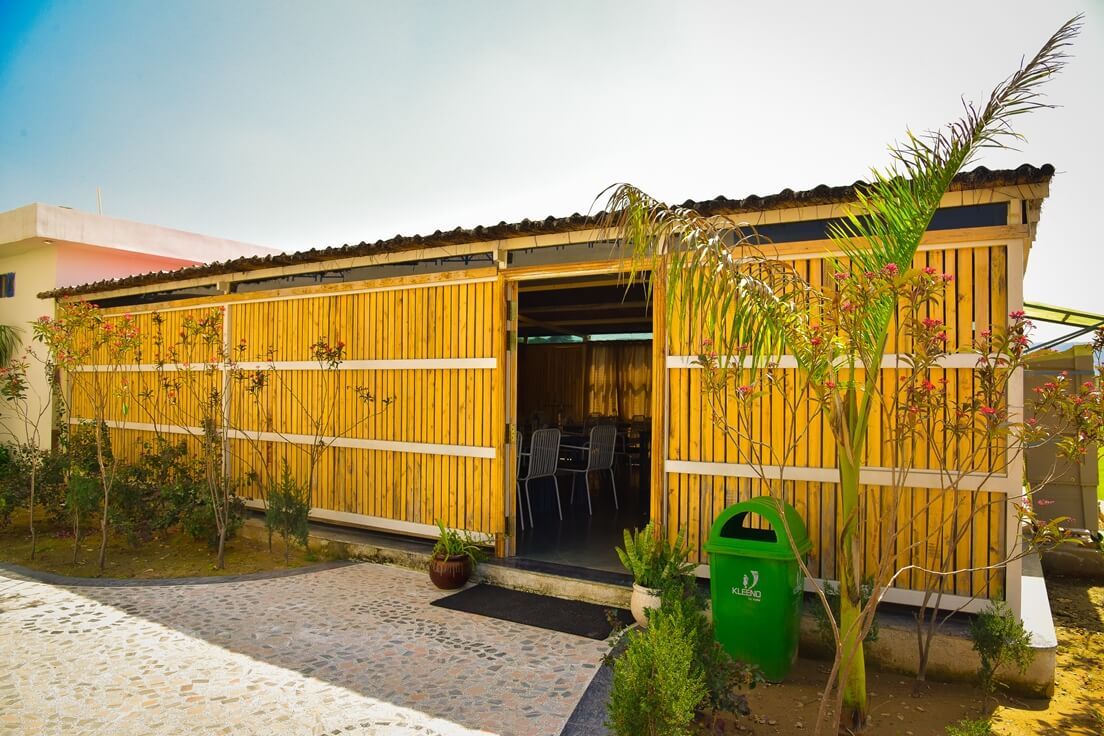 Un bâtiment à l’extérieur en bois, doté d’une entrée abritée et d’un espace extérieur aménagé pour s’asseoir.