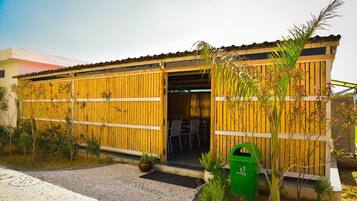 Un bâtiment à l’extérieur en bois, doté d’une entrée abritée et d’un espace extérieur aménagé pour s’asseoir.