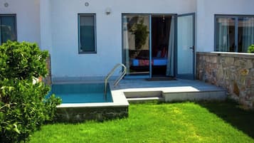 A modern house with a swimming pool, a stone wall, and a well-maintained lawn.