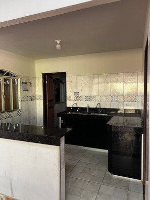 A kitchen with a black countertop, a sink, and a tiled backsplash.