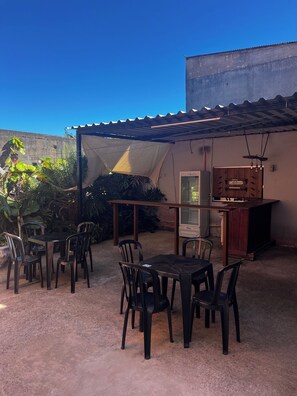 An outdoor patio with a table and chairs, a bar area, and a large umbrella providing shade.