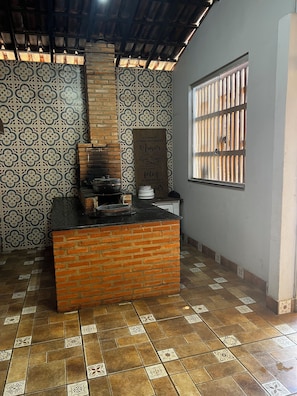 A kitchen with a brick counter, patterned tiles, and a window with bars.