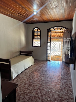 Una habitación con techo de madera, una cama, un ventanal y una puerta que da a un espacio exterior.