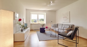 Un salon moderne avec un canapé, une table basse et une table d’appoint sur laquelle est posé un vase de fleurs.