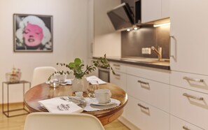 A modern kitchen with a dining table set for two, a vase with greenery, and a framed picture on the wall. - Your temporary home in beautiful Piesport on the Moselle (Piesport)