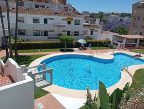 A residential area with a swimming pool surrounded by greenery and palm trees. - Pueblo del Parque Pool View
Apartment | South-Facing Terrace | Walk to Beach (Benalmádena)