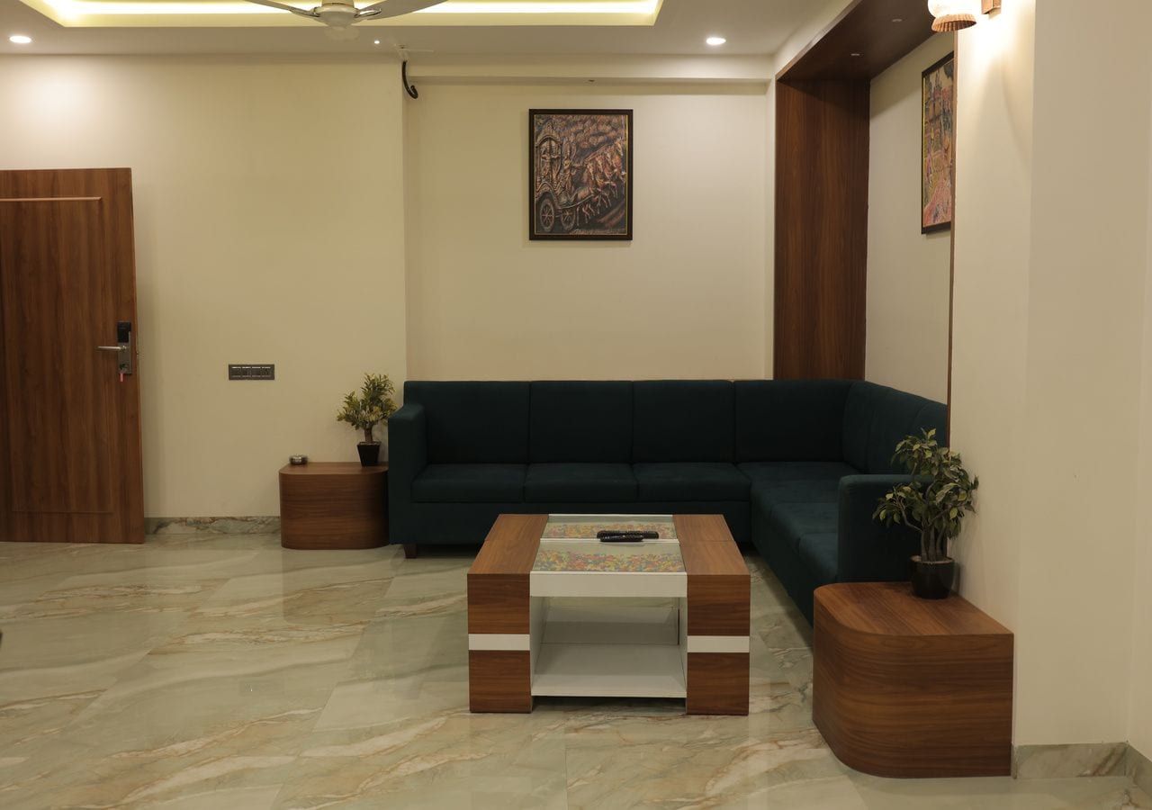 A modern living room with a dark green sofa, a wooden coffee table, and two side tables with potted plants.
