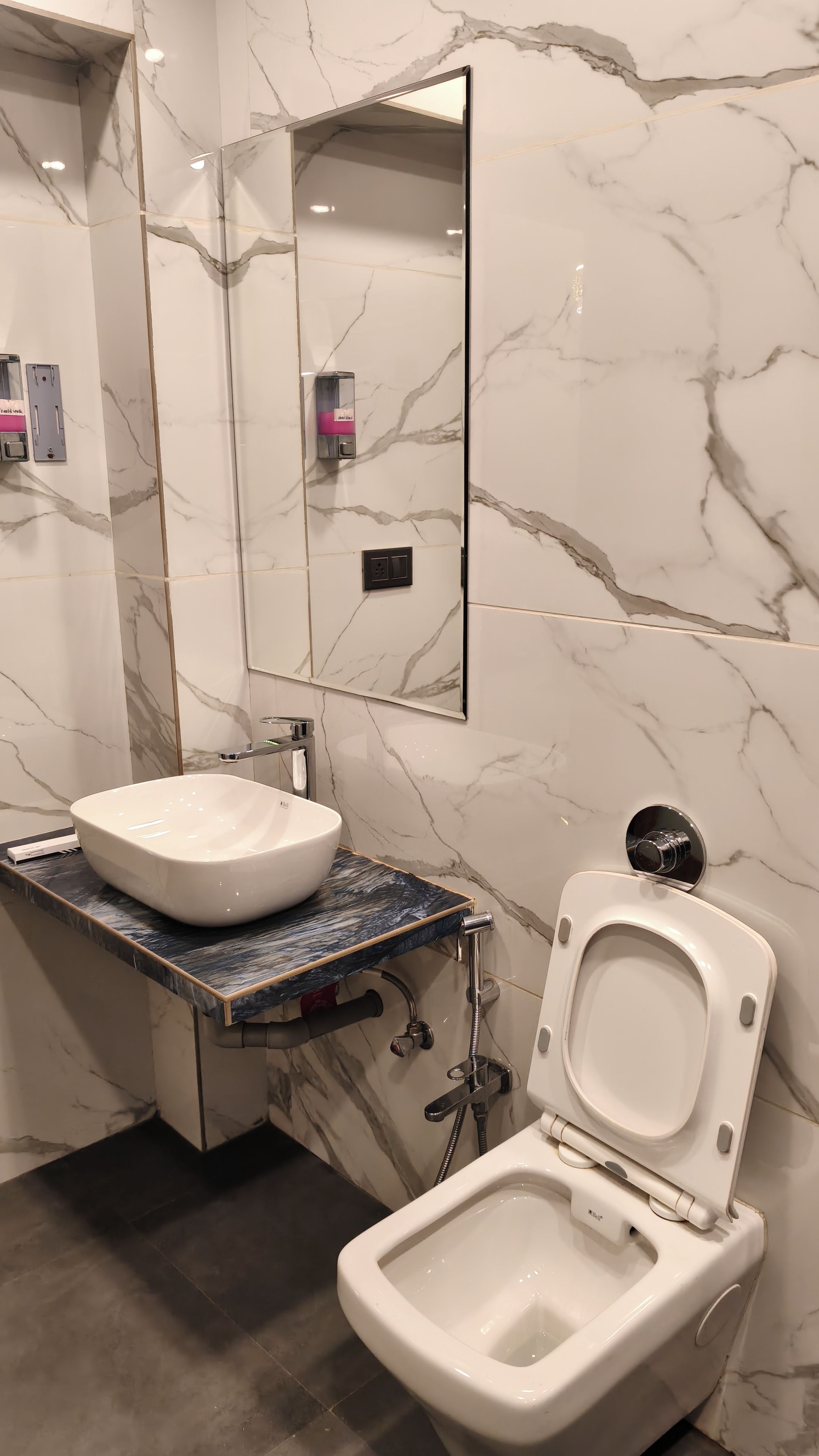Un baño con tocador de mármol, lavabo, inodoro y espejo.