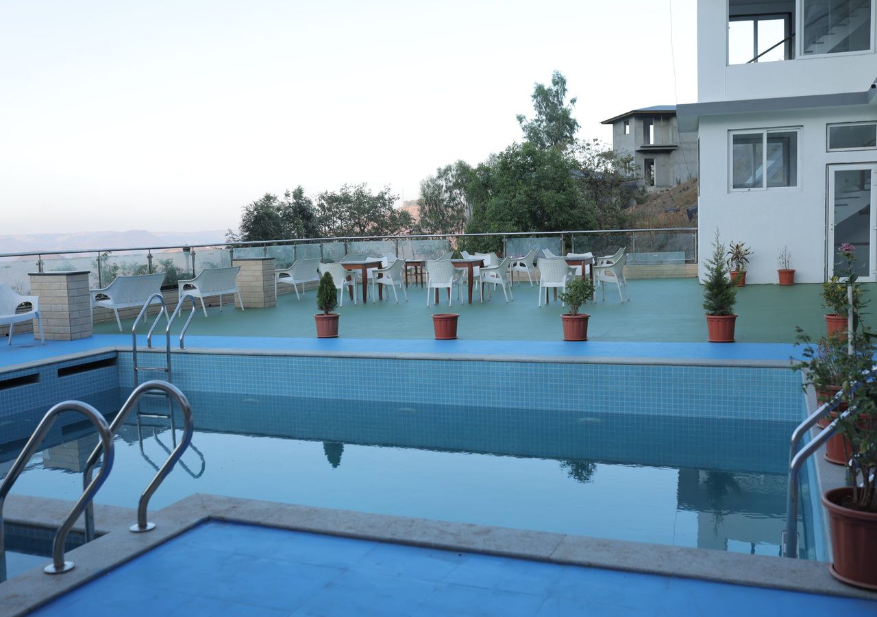 Una piscina con vistas a un edificio moderno y árboles al fondo.