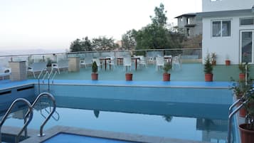Una piscina con vistas a un edificio moderno y árboles al fondo.