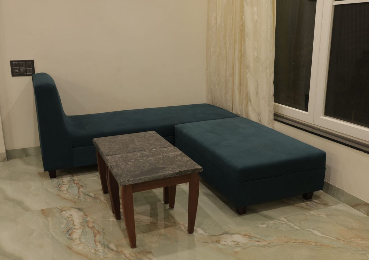 Una habitación con un sofá modular, una mesita y una ventana con cortinas.