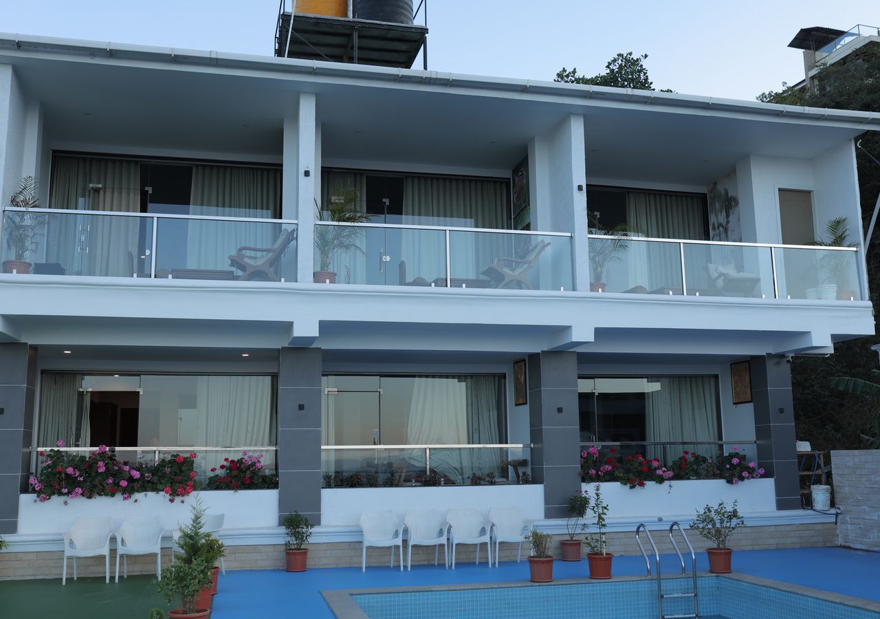A two-story building with a balcony, outdoor seating, and a pool.