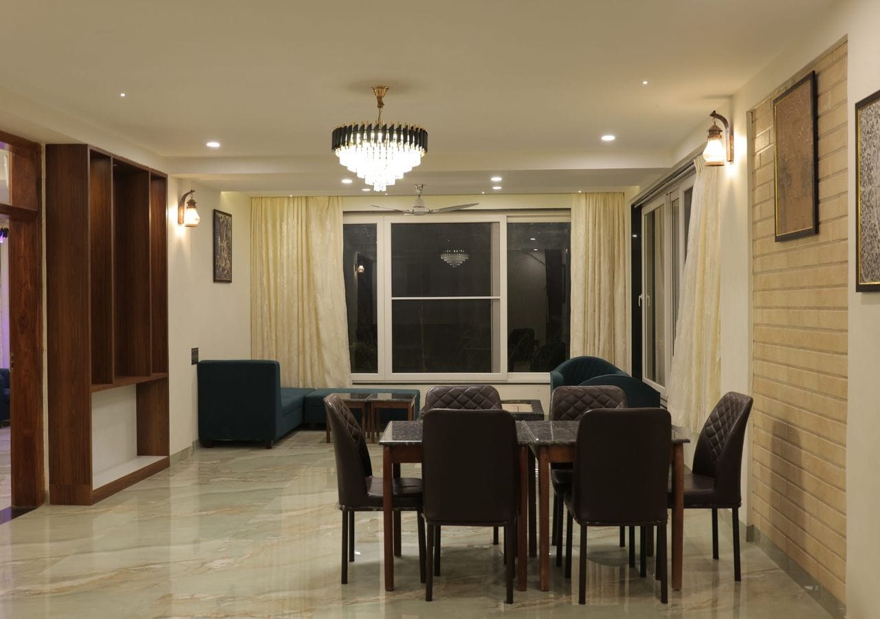 Un comedor con candelabro, una mesa de comedor con sillas, un sofá y un ventanal con cortinas.
