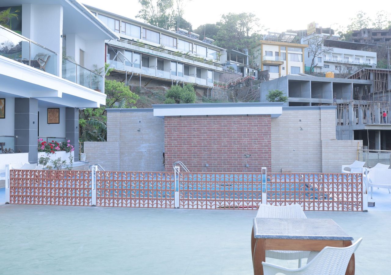 A courtyard with a brick wall, a metal gate, and a table with chairs.